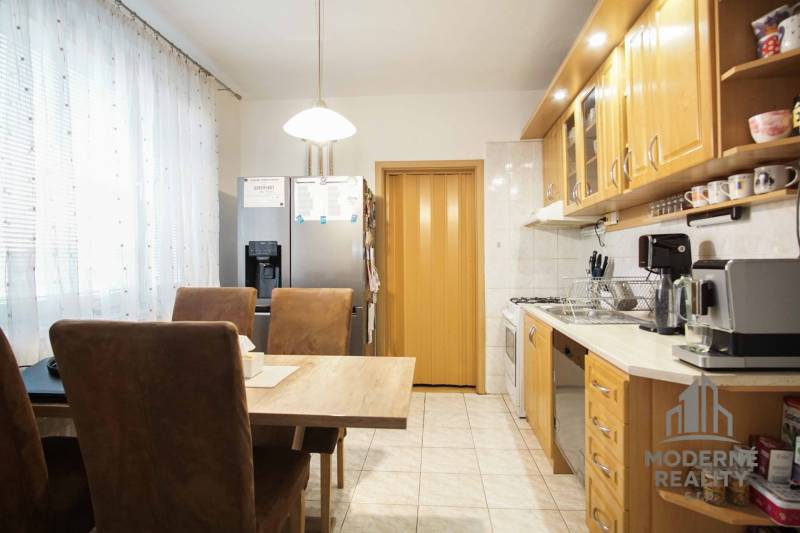 A kitchen in a 3-room apartment with a dining table, appliances, and light-colored furniture.