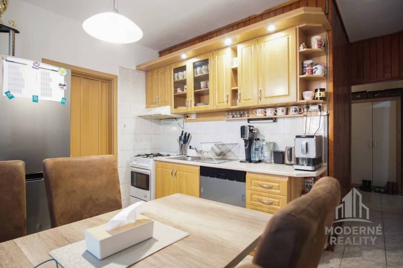A kitchen in a 3-room apartment with a light kitchen unit, appliances, and a table with chairs.