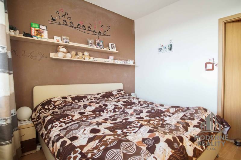 A bedroom in a 3-room apartment with a decorated wall and bold bed linens.