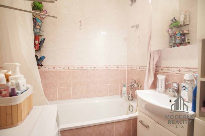 Bathroom with a bathtub and a sink in a 3-room apartment, tiles in soft shades.