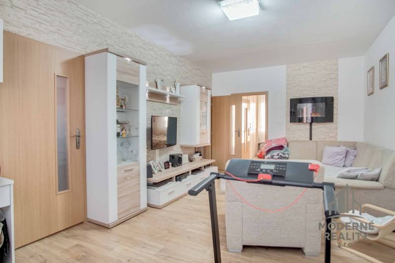 A living room in a 3-room apartment with a wooden decor floor and a corner sofa.