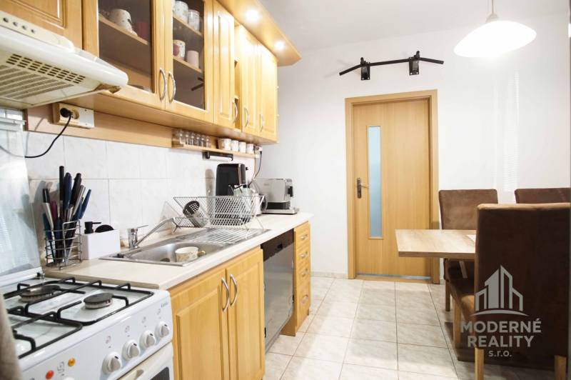 A kitchen in a 3-room apartment with wooden cabinets and a dining table.