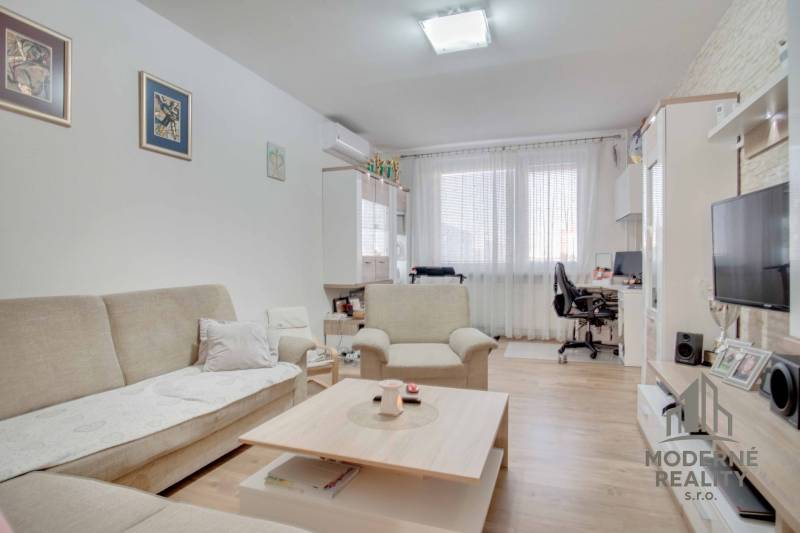 Living room with a sofa and TV in a 3-room apartment, floor with wooden decor.