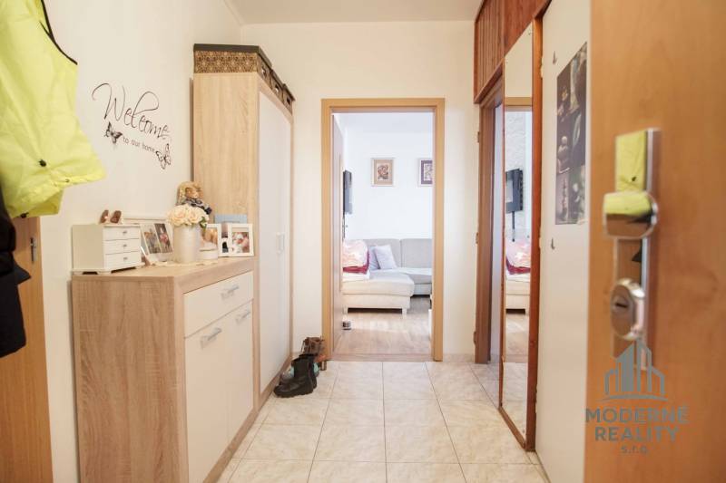 A hallway in a 3-room apartment with tiles and cozy furniture in a wooden decor.