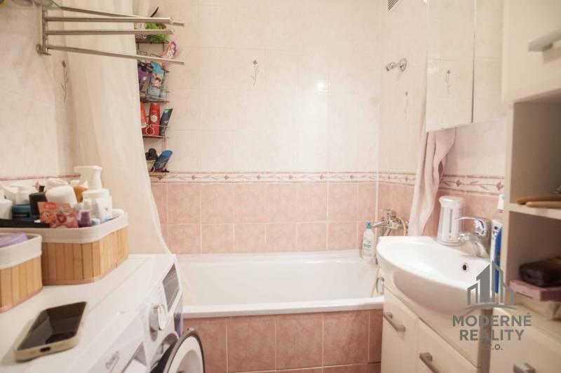 Bathroom in a 3-room apartment with a bathtub, sink, washing machine, and storage spaces.