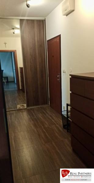 A hallway in a 2-room apartment with a wooden decor floor, a built-in wardrobe, and a mirror element.