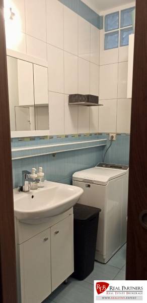 Bathroom with a sink, mirror, and washing machine in a 2-room apartment.