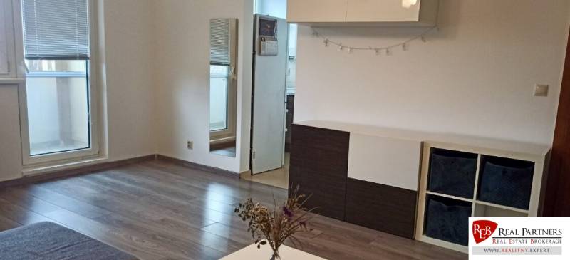 Living room in a two-room apartment with a wooden decor floor and access to the balcony.