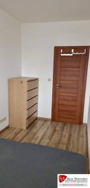 A room in a 2-room apartment with a chest of drawers and a wooden decor floor.