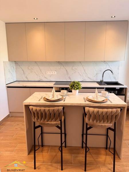 A kitchen in a 2-room apartment with a white marble countertop and a wooden decor floor.