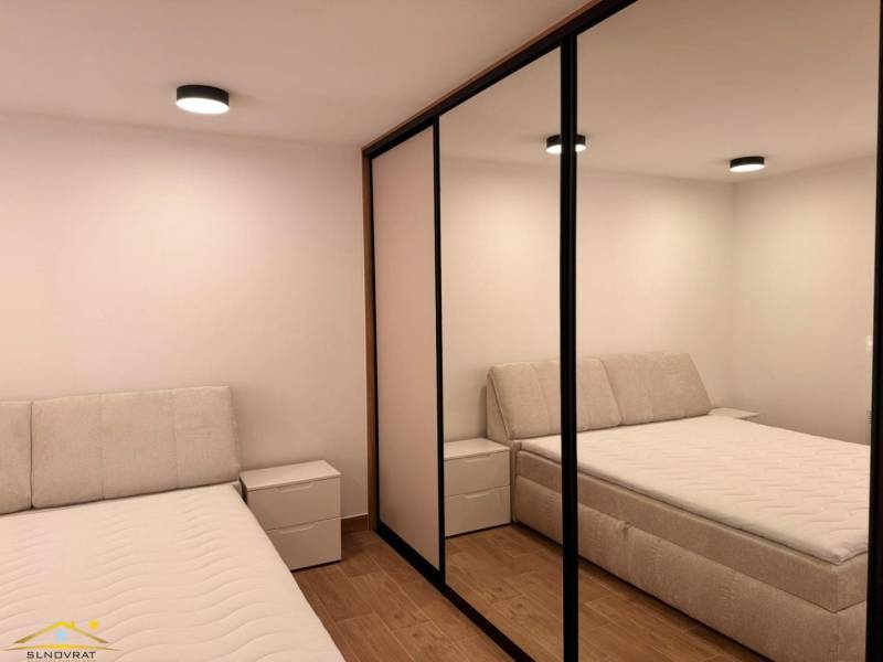 Bedroom with two beds, mirrored wardrobe, and wooden decor flooring in a two-room apartment.