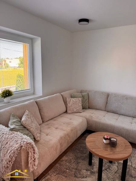 A comfortable sofa and a coffee table in a 2-room apartment with a view outside.