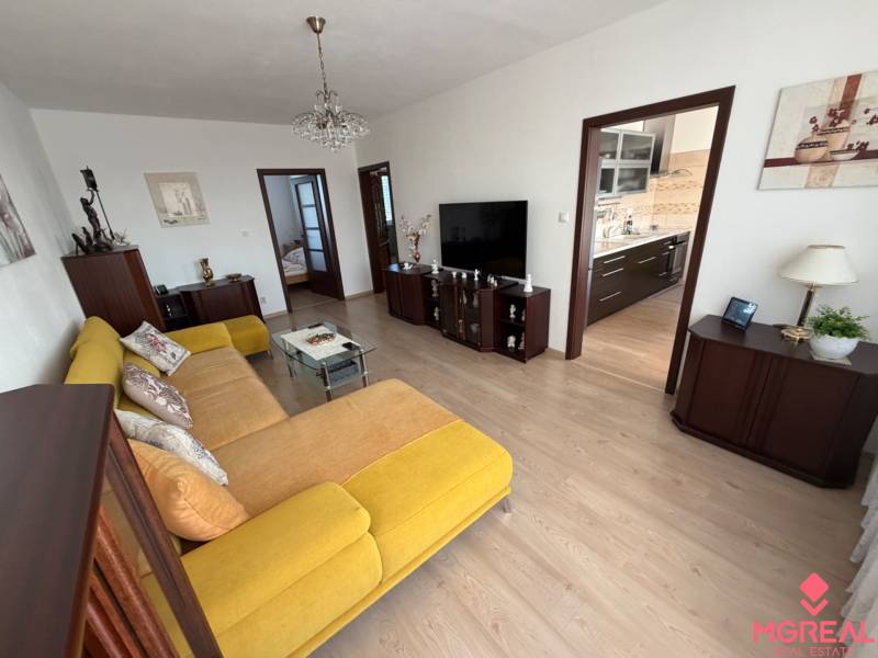 Living room in a 3-room apartment, yellow sofa, wood floor decor, spacious interior.
