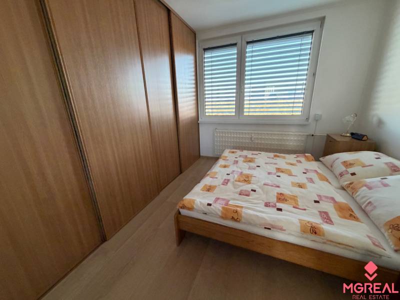 Bedroom in a 3-room apartment with a large wardrobe and bed, floor with wooden decor.
