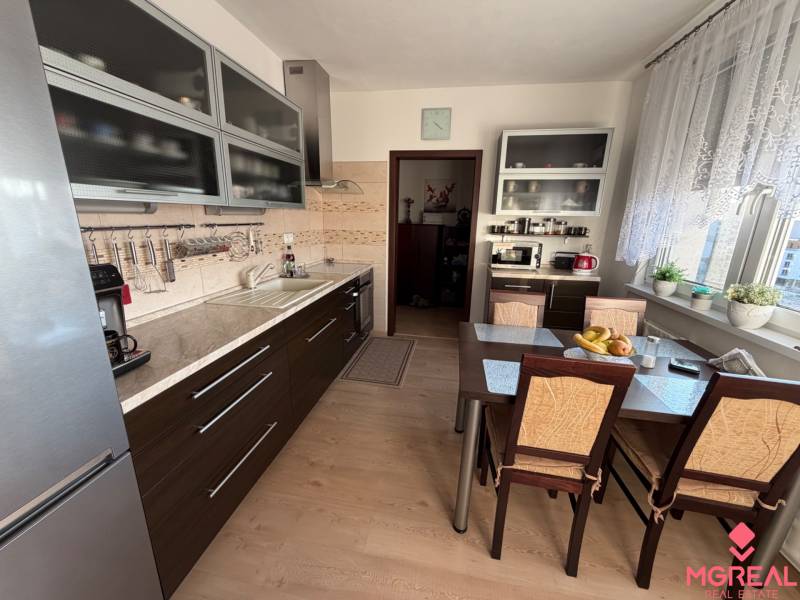 A kitchen in a 3-room apartment with a kitchen unit and a table, floor with wooden decor.