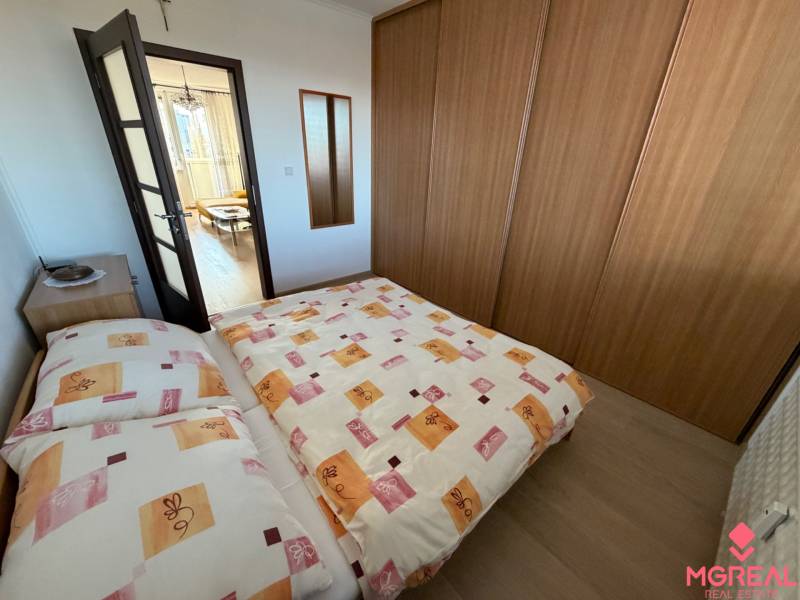 Bedroom in a 3-room apartment with a bed, built-in wardrobe, and floor with wooden decor.