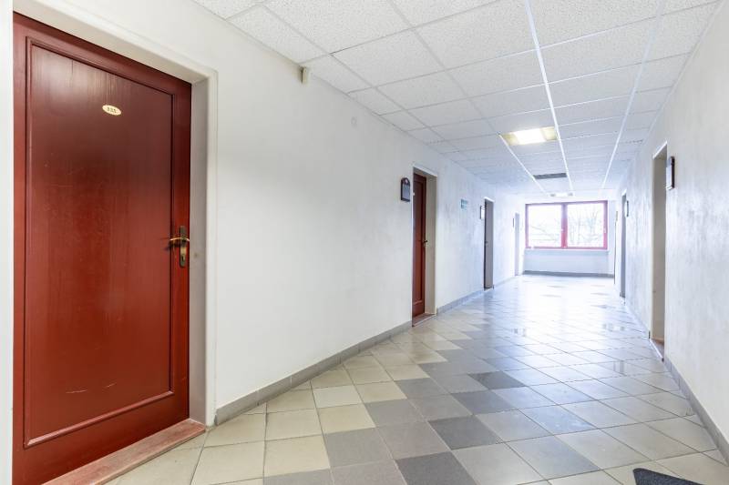 A tiled corridor leads to offices with wooden doors.