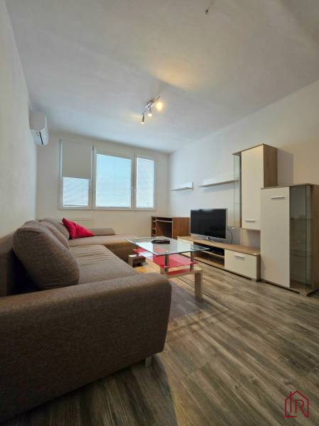 Living room of a two-room apartment with a corner sofa and a floor with a wooden decor.