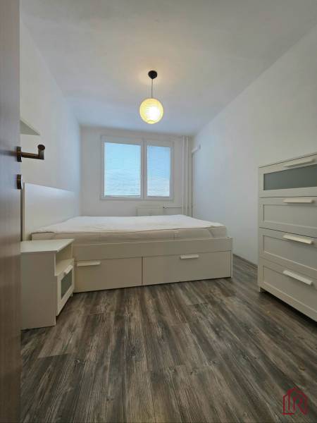 Bedroom in a 2-room apartment with a bed, light furniture, and a floor with a wooden decor.