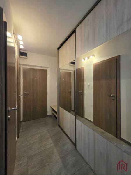 A hallway in a 2-room apartment with a large mirrored wardrobe and brown doors.
