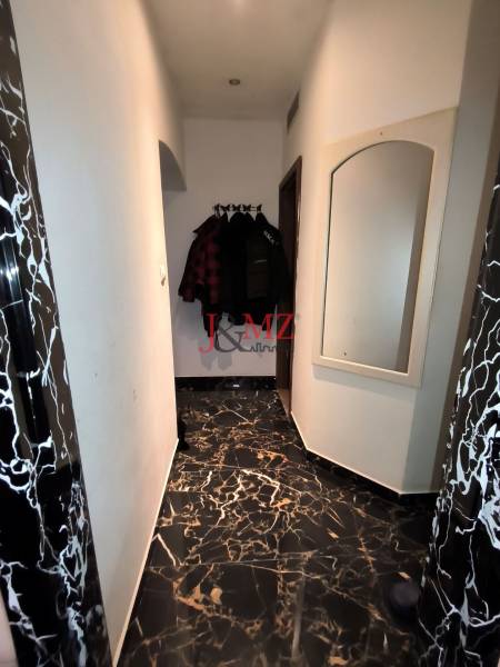 A hallway in a family house with a marble floor, a mirror, and coat hooks.