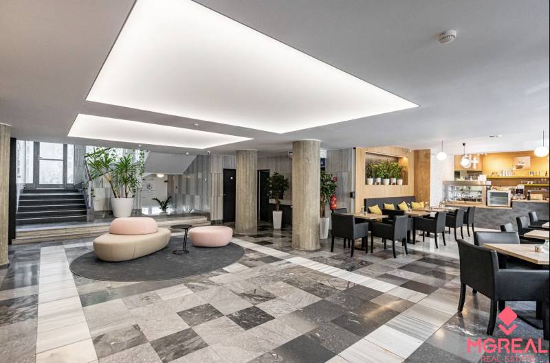 Offices with black and white flooring, columns, seating, and a café in the interior.