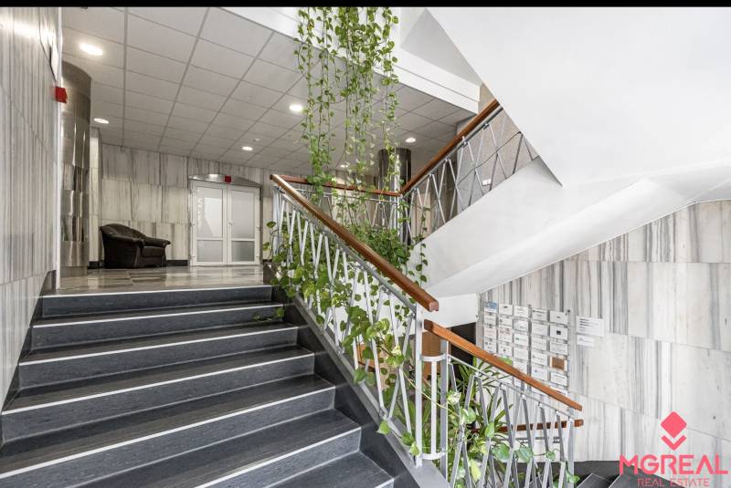 A staircase in the office with plants, a chair, and mailboxes.