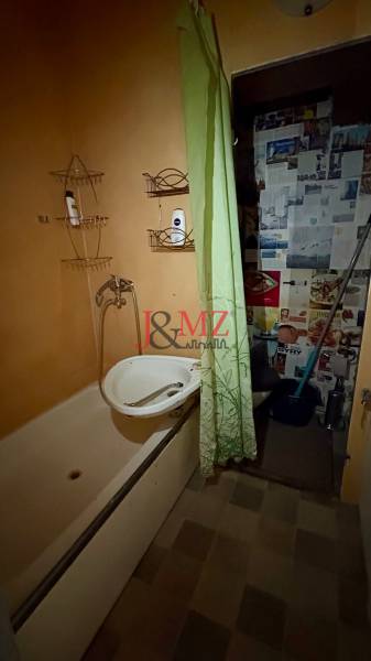 A bathroom with a bathtub and a green curtain in a studio apartment.