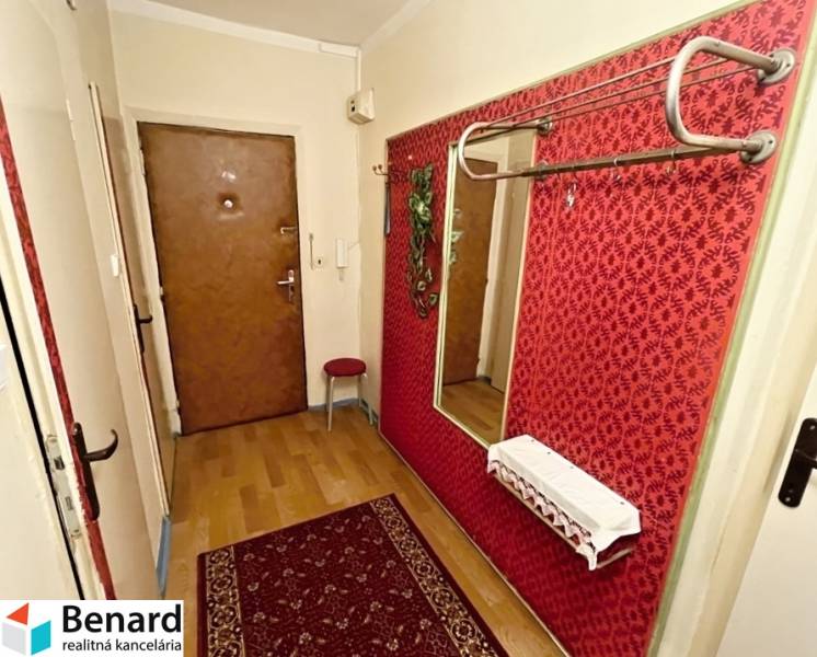 Combination of red wallpapers and a mirror in a 3-room apartment with a wooden decor floor.