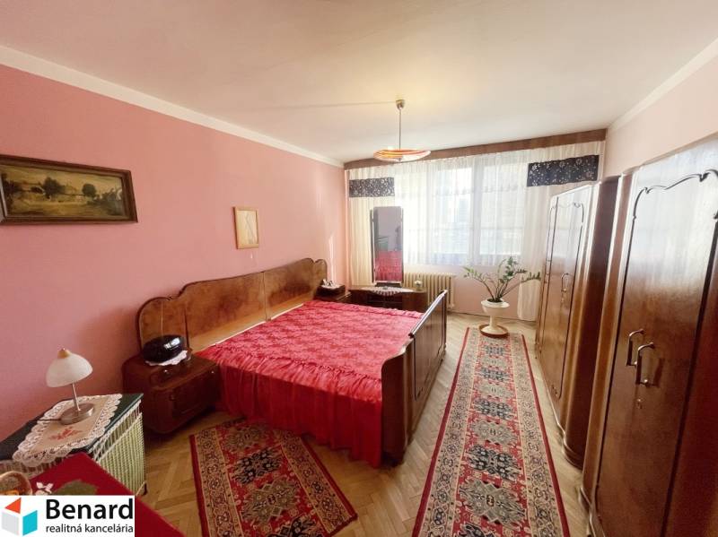 Bedroom in a 3-room apartment with red accessories and a floor with a wood decor.
