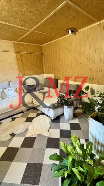 Interior of a family house with a corner sofa, plants, and patterned flooring with a wooden decor.