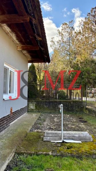 A family house in Mýtne Ludany with a side garden and lawn, surrounded by a fence.