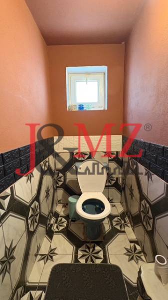 A bathroom in a family house with striking geometric tiles and orange walls.