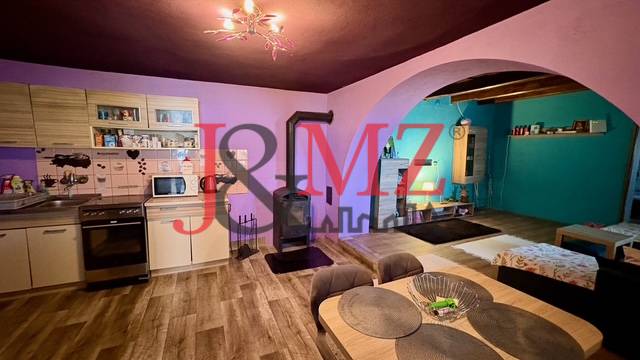 Kitchen and living room in a family house with a wooden decor floor and a fireplace.