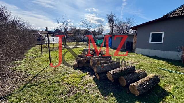 The courtyard of a family house in Mýtne Ludany with a stack of wood and fencing.