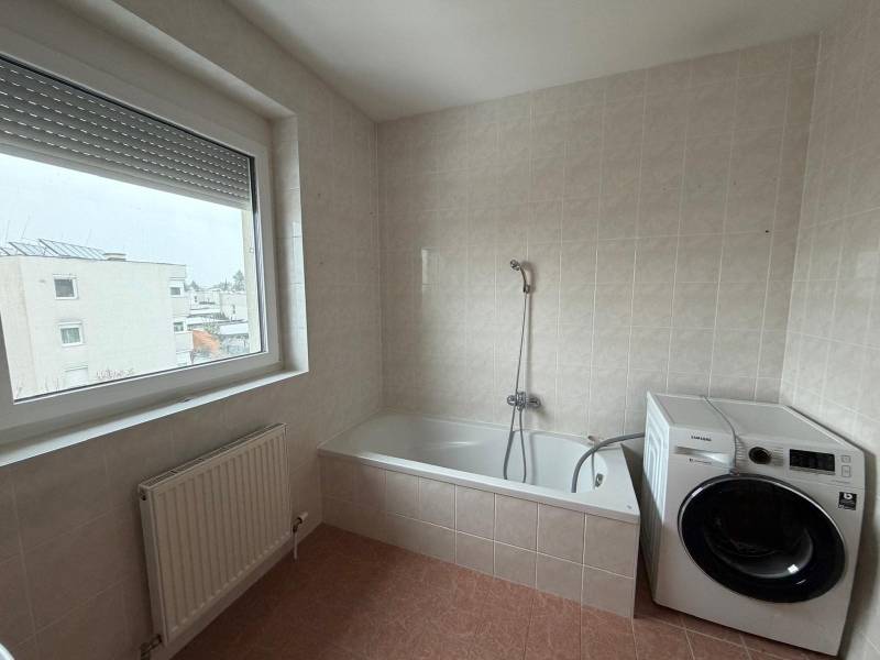 A bathroom in a 3-room apartment with a bathtub, washing machine, and a large window.