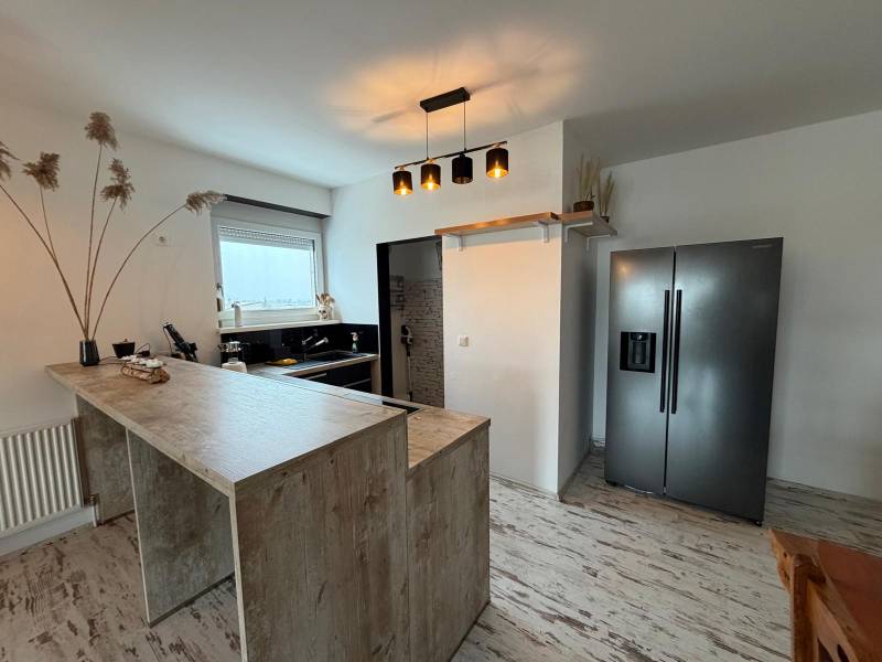A kitchen in a 3-room apartment with a counter and a wooden decor floor.