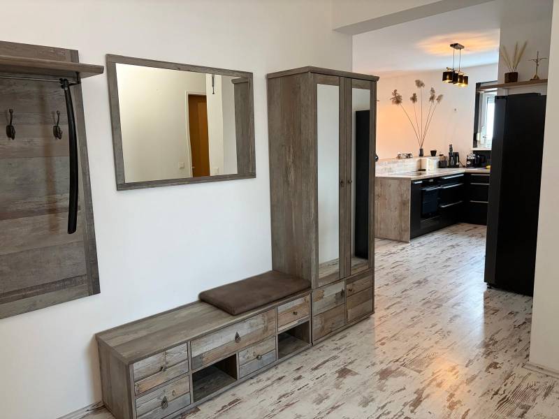 A hallway with wooden decor and a view into the kitchen in a 3-room apartment.