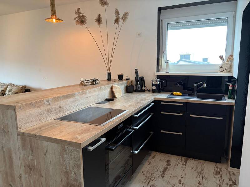 A kitchen in a 3-room apartment with black cabinets and a wooden decor floor.
