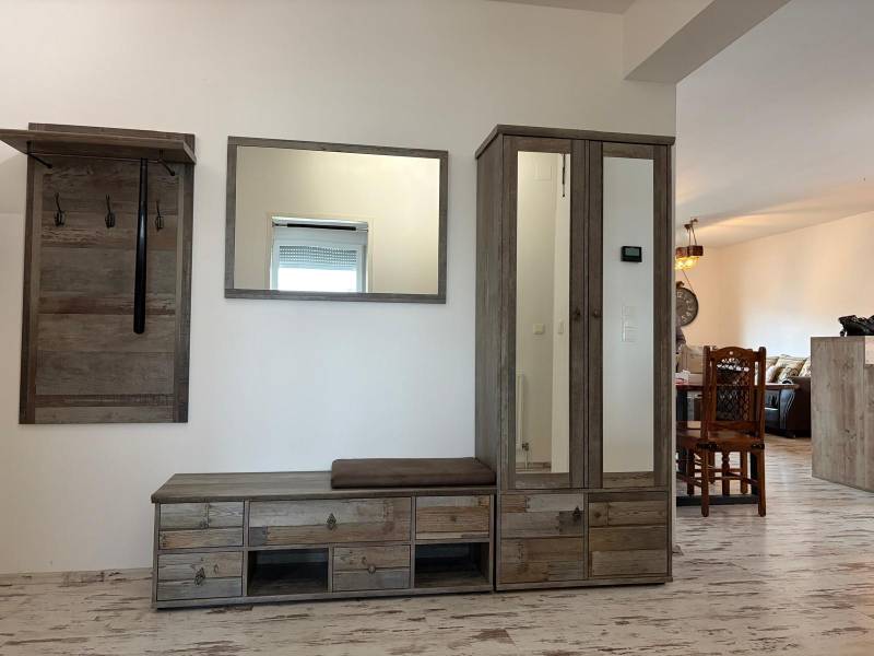 A hallway in a 3-room apartment with a coat rack and a wardrobe, floor with a wooden decor.