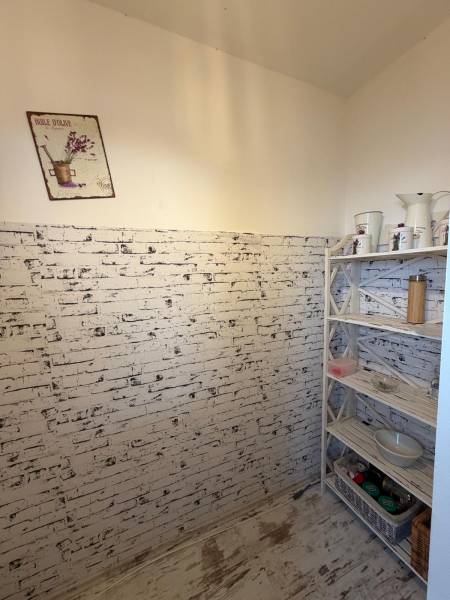 A room with wallpaper imitating bricks, a shelf with supplies and decorations.
