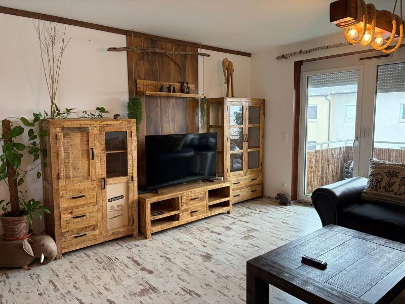 A living room in a three-room apartment with wooden furniture and a wooden decor floor.