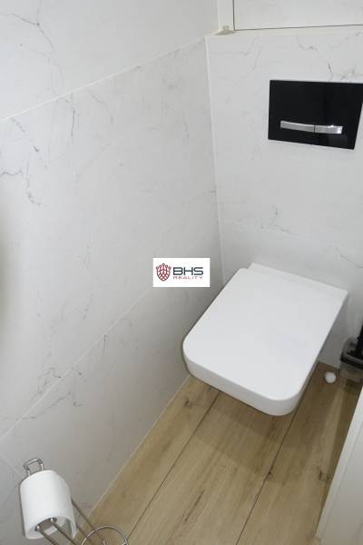 Bathroom with toilet and wooden decor flooring in a 3-room apartment.