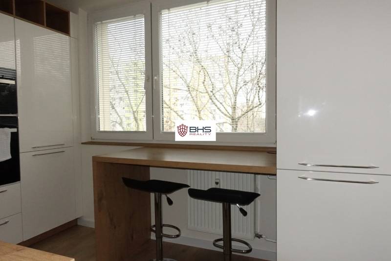 The kitchen of a three-room apartment with a wooden decor floor and large windows.