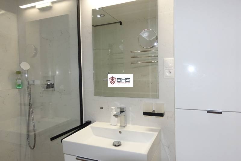 A bathroom in a 3-room apartment with a sink, mirror, and shower corner.