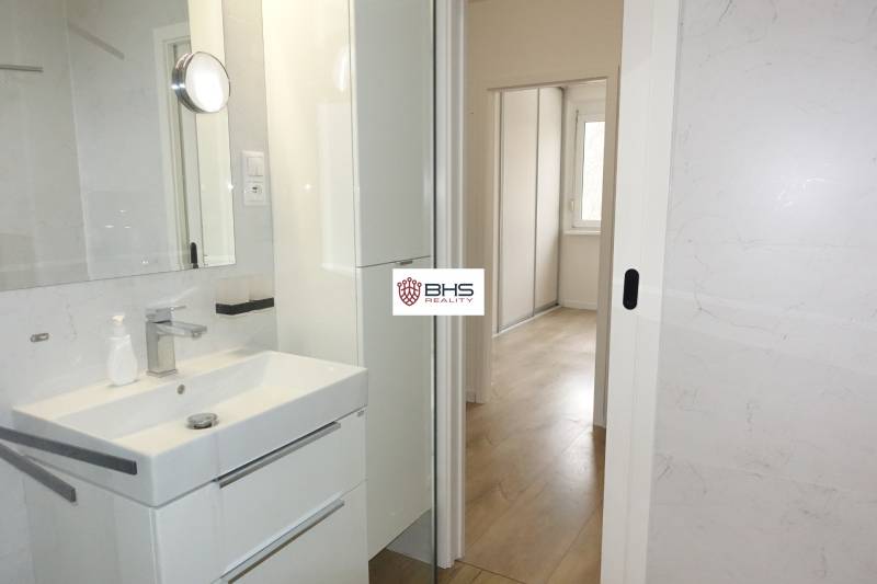 Bathroom with a sink, white cabinet, and a view into the hallway in a 3-room apartment.