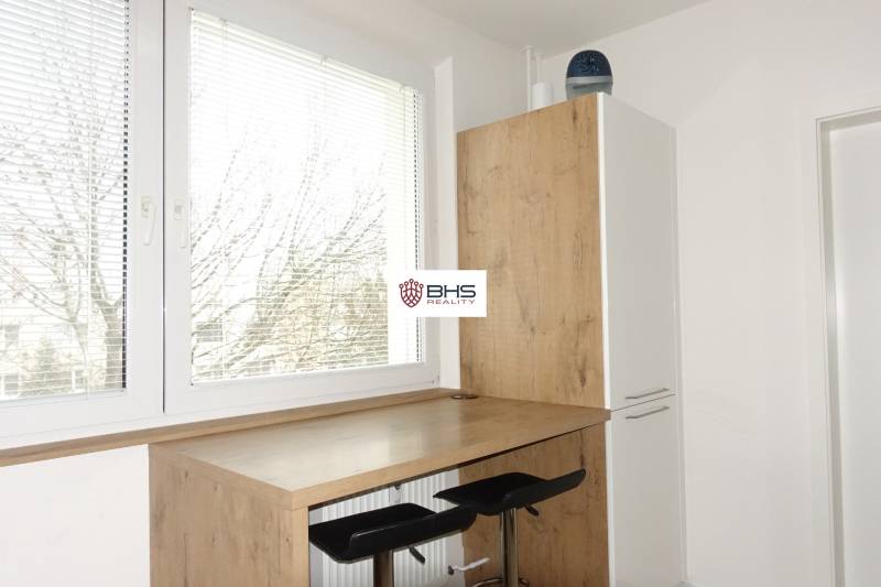 The kitchen of a three-room apartment with stools and a table with a wooden decor, sunny window.