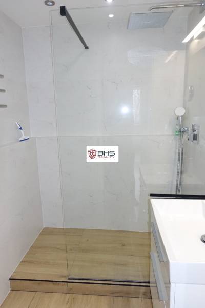 Shower enclosure with glass and floor with wood decor in a 3-room apartment.