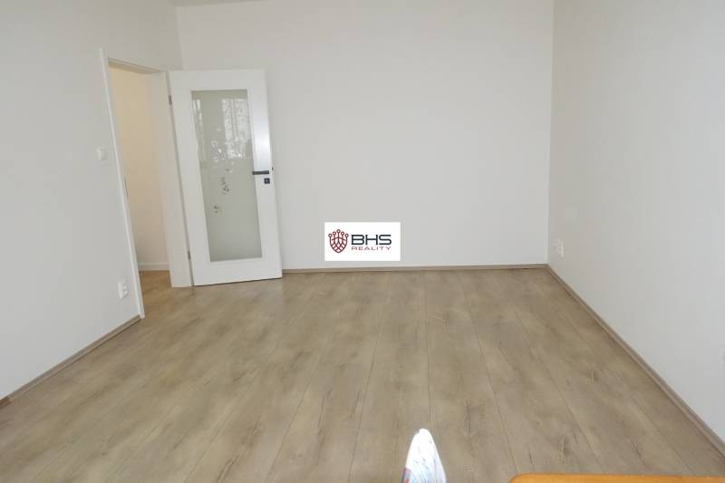 A room in a 3-room apartment with white walls and a wooden decor floor.
