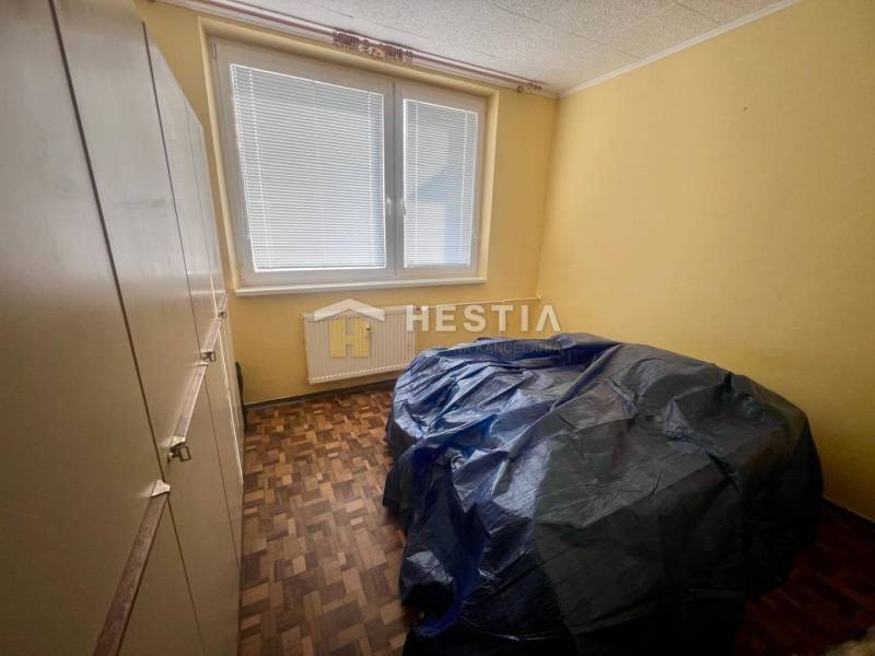A room in a 3-room apartment with yellow walls, parquet flooring, large window.